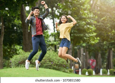 Young Asian couple jumping and having fun in local park