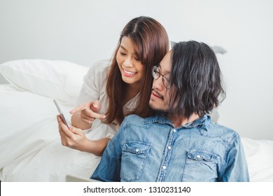 Young Asian couple lover using phone and laptop in bedroom for relax, Asian couple lover for Valentine concept