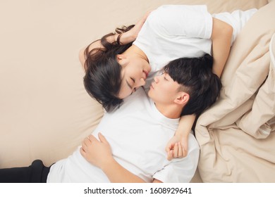 A young asian couple is lying in bed, looking at each other, very close
 - Shutterstock ID 1608929641