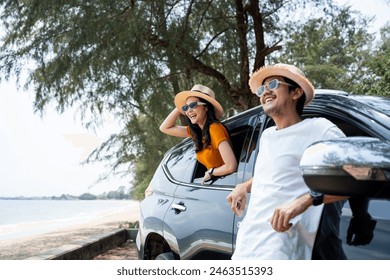 Young asian couple man and woman travel by car on a bright day to the sea sand beach with beautiful blue sky sunlight. They was happy along the way trip. safety driving car vacation. - Powered by Shutterstock