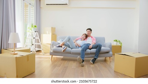 young asian couple moving into new home - they sitting on sofa together