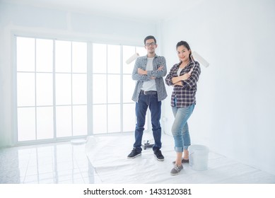 Young Asian Couple Painting Their New House Wall By Them Self,DIY Concept.