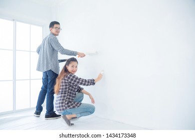 Young Asian Couple Painting Their New House Wall By Them Self,DIY Concept.