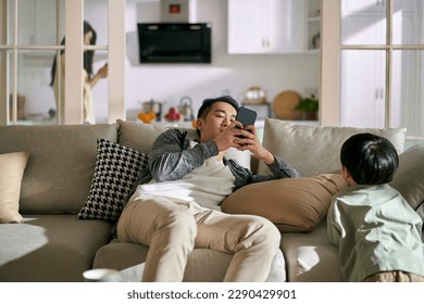 young asian couple parents addicted to smartphones ignoring child, concept for smartphone or social media addiction