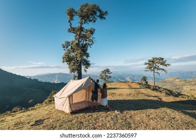 Young asian couple pitch a tent in campground on mountain hill in national park on summer vacation. Leisure activity and Recreational pursuit