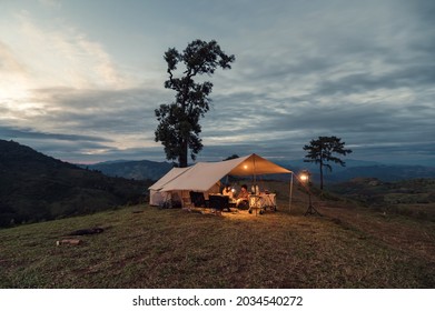 Young asian couple resting in large tent pitched on hill in the evening at countryside - Shutterstock ID 2034540272
