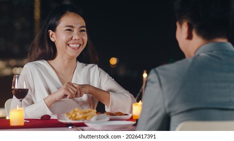 Young asian couple romantic dinner in rooftop restaurant at night city with happy moment celebrate anniversary relationship. Love relationship, elegant celebrating at rooftop restaurant concept.