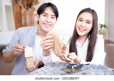 Young Asian Couple Is Saving Money For Their New Home. Happy Young Couple Inserting Coin In Piggybank.saving For Life Insurance ,wealthy Retirement Concept.
