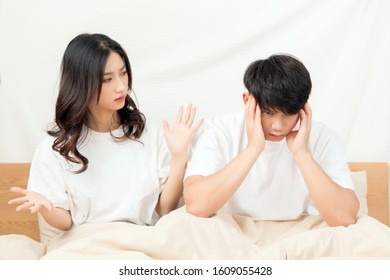 A Young Asian Couple Sitting On A Bed In Short White Sleeves Are Arguing