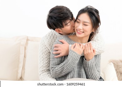 A Young Asian Couple Is Sitting On A Sofa In Winter