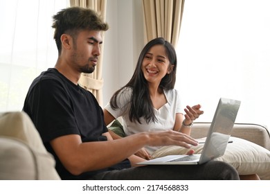 Young Asian couple  sitting on sofa together while a man looking on laptop, Domestic life and Domestic home concept.