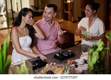 Young Asian Couple Testing Massage Oils In Luxury Beauty Salon. Spa Therapist Explains About Natural Ingredients They Use For Beauty Procedures. Weekend Date, Celebrating Honeymoon Or Anniversary.