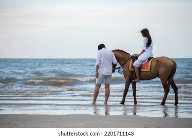 Young Asian Couple Walking With Horse On The Beach In Sunny Summer Day.