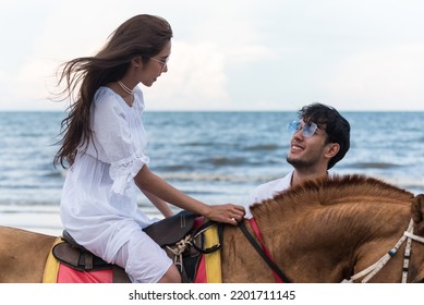 Young Asian Couple Walking With Horse On The Beach In Sunny Summer Day.