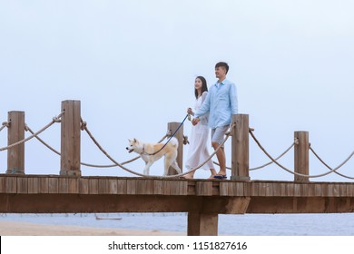 Young Asian Couple Walking On Pier With Pet Dog.