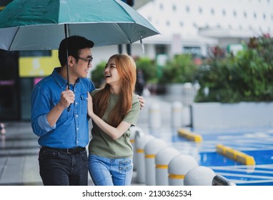 Young Asian Couple Walking In The Rain