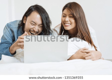Young Asian couple watching movie with laptop in the bed
