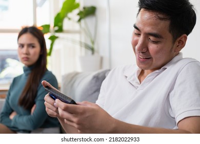 Young Asian couple in which the man plays the game and ignores his wife. His wife's face was filled with indignation. - Shutterstock ID 2182022933