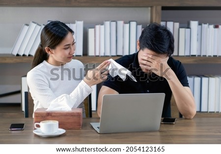Young asian couples spend time together in the library. A girlfriend offered a tissue to a sad man who is suffering from a thesis project he is doing.