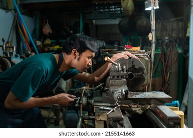 A Young Asian Craftsman In A Small Factory, A Family Business, Was Standing Closely To Control The Lathe, Carefully, And Had A Serious Expression.