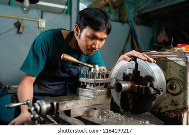 A Young Asian Craftsman In A Small Factory, A Family Business, Was Standing Closely To Control The Lathe, Carefully, And Had A Serious Expression.