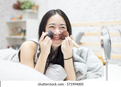 Young Asian Cute Woman Make Up Her Clear And Pure Face On Her Bed In The Bedroom With Smile And Happy Mood (shallow Depth Of Field)