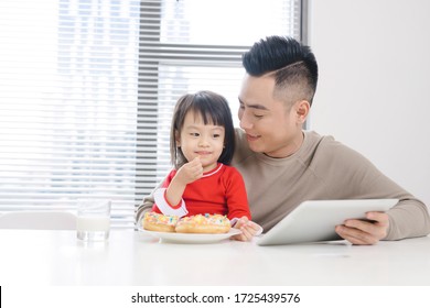 Young Asian Dad And Daughter Eating Pizza While Watching On Ipad.