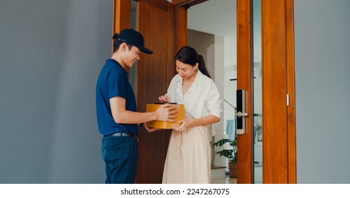 Young Asian delivery man in blue navy uniform knock door home delivery online shopping box to woman customer in front door and woman sign name accept on smartphone at house. home delivery concept. - Powered by Shutterstock