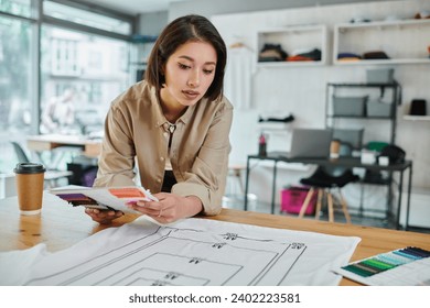 young asian designer with color palette near clothes with format sizes in print studio, creativity - Powered by Shutterstock