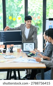 Young Asian developer presents mobile app UI UX wireframes and code to colleagues in a collaborative office brainstorm session, ideal for tech and startup concepts.