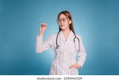 Young asian doctor put hand in pocket of medical uniform lab coat and stethoscope on blue background. Smiling female doctor showing thermometer. Medical care, healthcare, health insurance concept. - Powered by Shutterstock