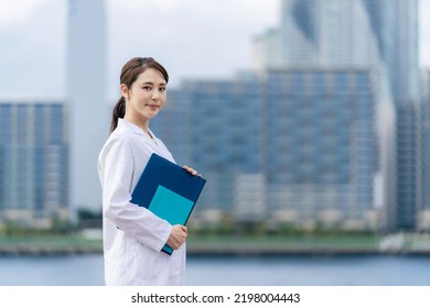 Young Asian Doctor Smiling In Front Of The City.