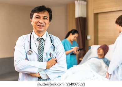 Young Asian Elder Man In Medical Robe Smiling And Looking At Camera During Work Against At Clinic.. Healthcare Medical Checkup Concept.