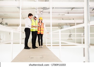 Young Asian engineer or building inspector checking interior building detail with female construction worker by using check list and drawing. Two building worker inspecting interior building.
