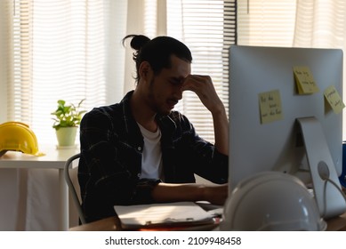 Young Asian engineer designer employee feel bad stress or sad due to job problem work load or personal financial bankrupt situation while sitting alone in office room. Salaryman mental problem concept - Shutterstock ID 2109948458