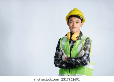 A young Asian engineer in a light green robe stands confidently with his arms crossed and looking at the camera. on a white background - Powered by Shutterstock