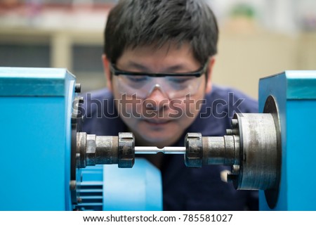 young asian engineer set up and testing test piece machine in the laboratory factory, engineering and industrial concept