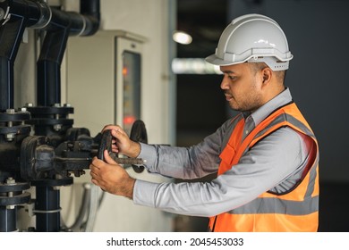 Young Asian Engineer Working At Valve Water Pump Checking And Maintenance For The Safety. Worker Control The System Water Of The Building.