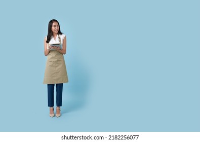 Young asian entrepreneur woman in apron hand holding tablet for list order food isolated on blue background. Barista and waitress service concept. - Powered by Shutterstock