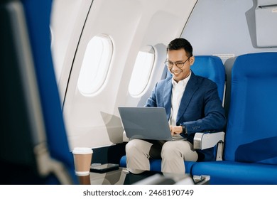 Young Asian executive excels in first class, multitasking with digital tablet, laptop and smartphone. Travel in style, work with grace.
 - Powered by Shutterstock