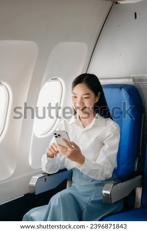 Young Asian executive excels in first class, multitasking with digital tablet, laptop and smartphone. Travel in style, work with grace.

