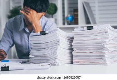 Young asian exhausted businesssman with messy desk and stack of papers, working busy, overwork.