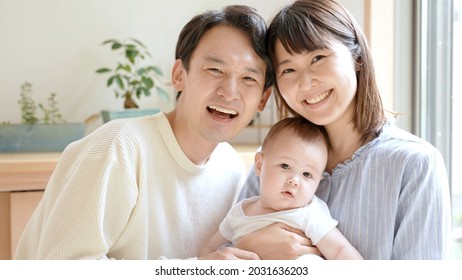 Young Asian Family With Baby Looking At Camera