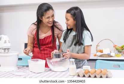 Young Asian family cooking food in kitchen. Happy teenage girl with her mother mixing batter in the bowl together. good team,Time of happiness. vacation holiday and Cooking together concept