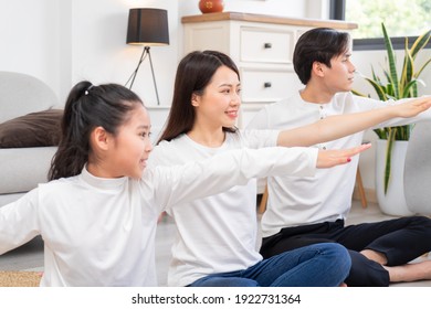 Young Asian Family Doing Exercise Together At Home
