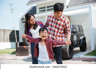 Young Asian Family With Kid In Front Of Their House And Car