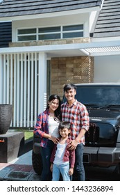 Young Asian Family With Kid In Front Of Their House And Car