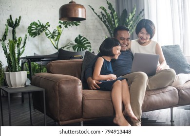 Young Asian Family Looking At The Laptop Together At Home.