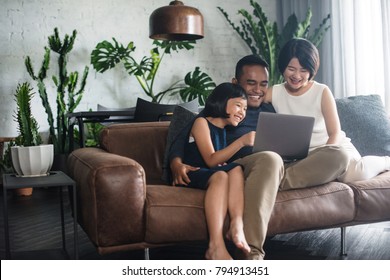 Young Asian Family Looking At The Laptop Together At Home.