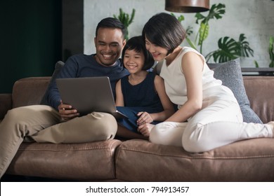 Young Asian Family Looking At The Laptop Together At Home.